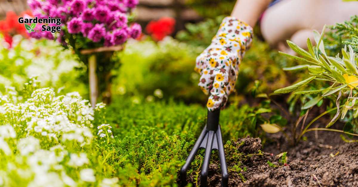 A gloved hand with a floral pattern uses a garden fork to cultivate the soil in a lush garden. The background is vibrant with a diverse array of blooming flowers, showcasing a well-maintained garden with a rich, earthy ambiance.